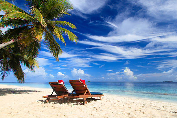 two chair lounges with red Santa hats on beach stock photo