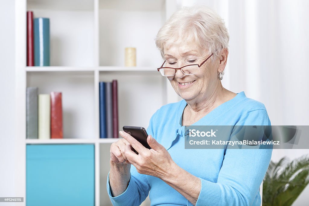 Texting senior Smiley senior woman texting on mobile phone Active Lifestyle Stock Photo
