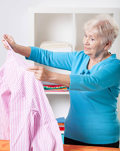 istock Elderly woman folding shirt 491246733