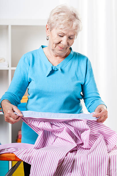 istock Elderly woman preparing shirt to ironing 491246803