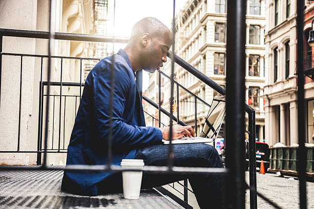 istock Man texting on laptop seated on steps on the streets 491247690