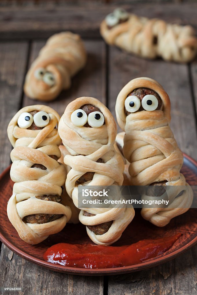 Sausage meatballs mummies in dough scary halloween food celebration party Sausage meatballs mummies in dough scary halloween food celebration party with funny eyes on vintage wooden background. Rustic style and natural light 2015 Stock Photo