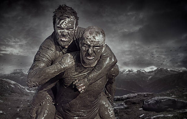 cortados homem de transporte amigo durante uma corrida na lama - mud run imagens e fotografias de stock