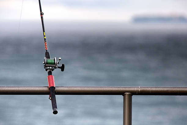 Fishing reel and rod attached to the railing stock photo