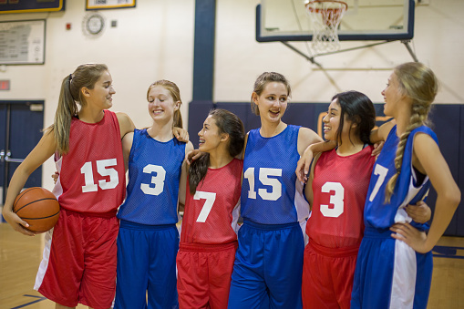 Teenage girls playing high school basketball in uniforms