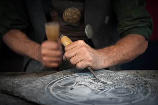 Craftsman hands working on a slate plate