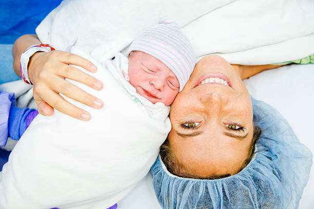 Cesarean Section C-Section Birth Mother and Newborn First look after Cesarean Section C-Section Birth. Mother smiling at view with her Newborn following surgery. unknown gender stock pictures, royalty-free photos & images