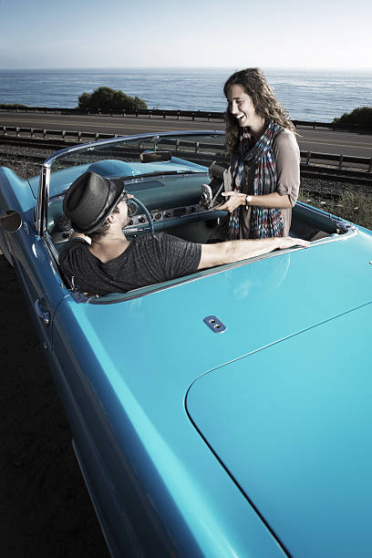 istock Couple Taking a photo with a Antique camera in a Convertible 491311084