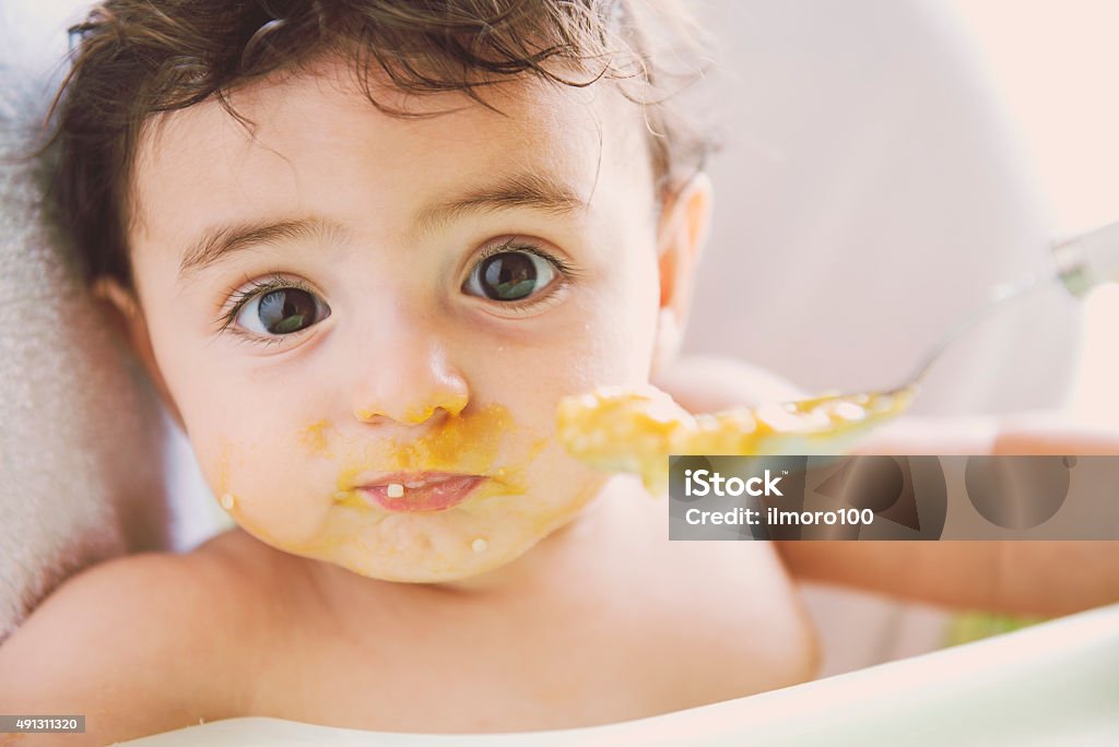 Feeding the baby lunch or dinner time for baby in his high chair Baby - Human Age Stock Photo