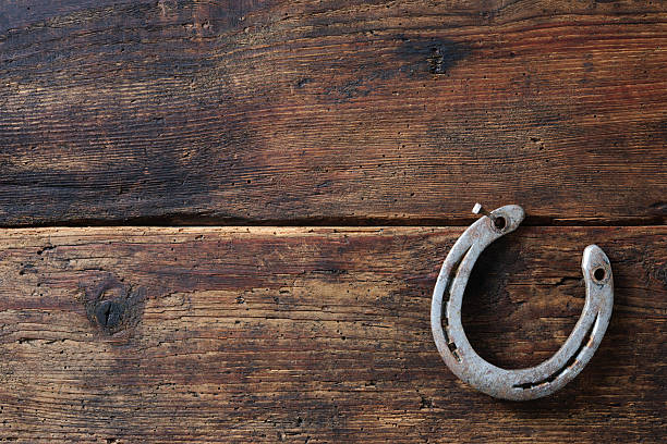 Old rusty horseshoe Old rusty horseshoe on vintage wooden board good luck charm photos stock pictures, royalty-free photos & images