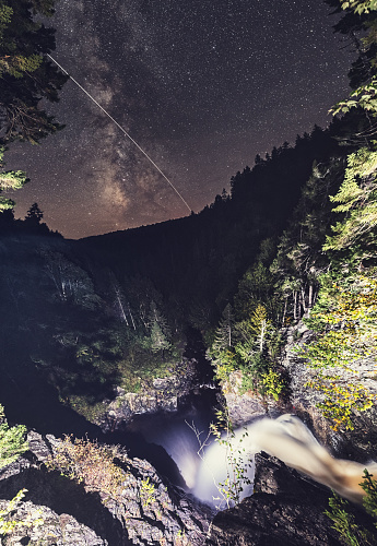 The International Space Station is set against the Milky Way orbiting high above North River waterfall in Northern Nova Scotia. Long exposure with light painting.