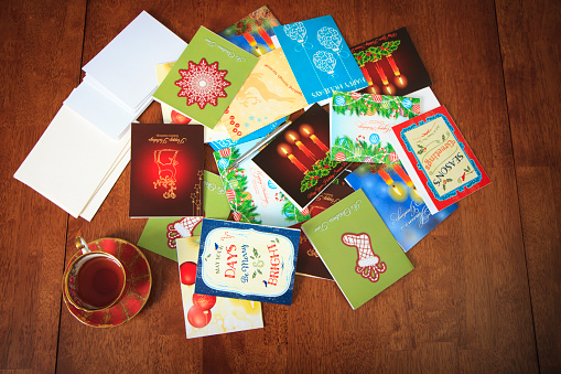 Woman Reaching For Holiday Cards On Table 