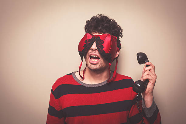 istock Man with bra on face holding telephone 491323025