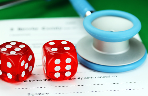 A Doctors light blue colored stethoscope with two red dice placed along side of it, both resting on a doctors sick certificate pad, asking the question do you gamble with your health.