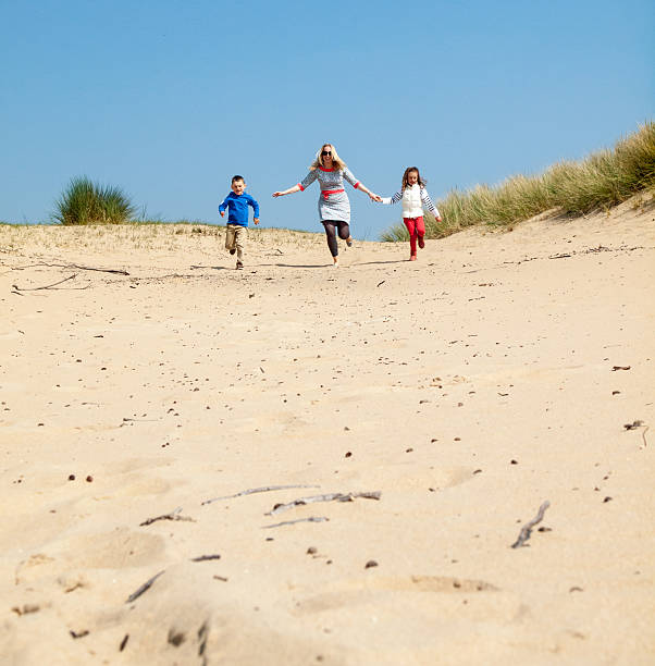 istock woman and small  children running through sand dunes 491326853