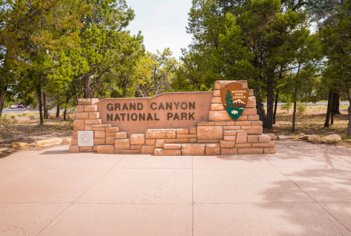 Grand Canyon National Park, Arizona - April 22, 2014: A human made sign constructed out of concrete, bricks, and other natural materials to welcome visitors to the Grand Canyon. Two additional signs are attached stating \