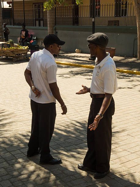 Falmouth, Jamaica – February 12, 2015: View of two locals talking on the street near the Falmouth Cruise Port, along with a building and a street vendor in Falmouth, Jamaica