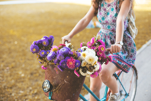 Beautiful woman on a bicycle with a basket full of flowers