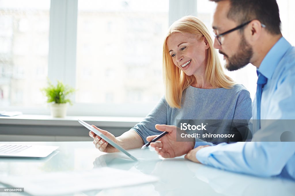 Looking at data Two colleagues looking at data in touchpad while businessman giving explanations 2015 Stock Photo