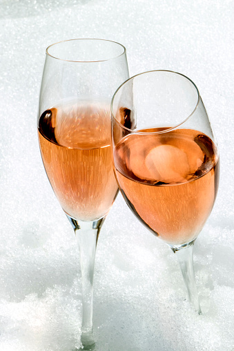 Flute glasses of rosé champagne on the snow.