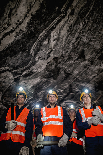 Group of miners working at the mine underground and wearing protective wear