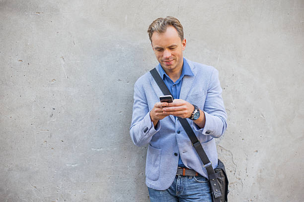 istock Man standing by the wall and using smartphone 491351318
