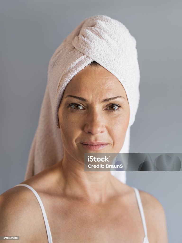 Mature woman with towel wrapped around her head. Portrait of mature woman with towel wrapped around her head. She is looking at the camera. 2015 Stock Photo