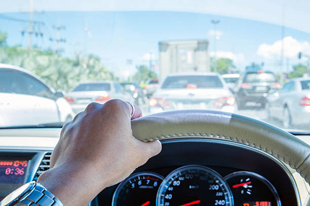 istock Hand of driver holding steering wheel, with traffic view 491360456