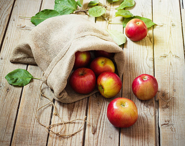istock Ripe red apples in a bag on wooden background 491360804