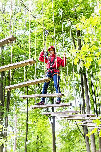 istock Kid walking on rope bridge in climbing course 491360806