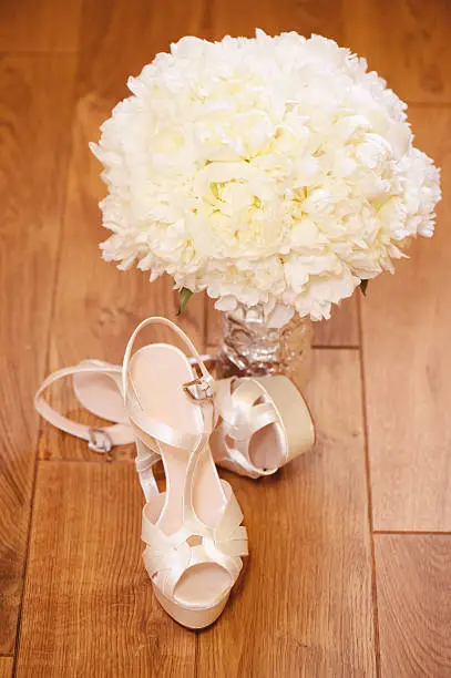 Beautiful wedding bouquet with bride's shoes on wooden floor