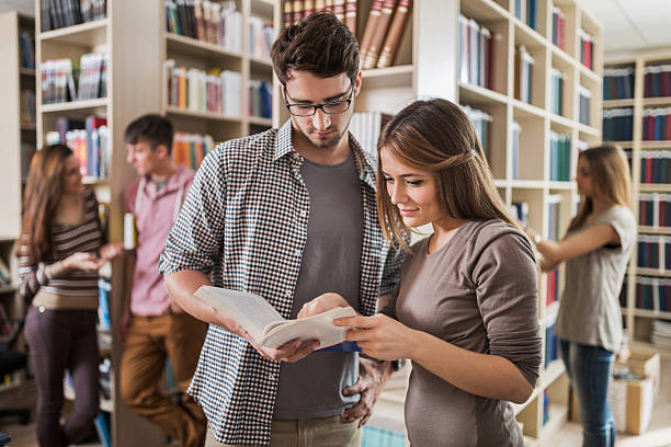 istock Young couple reading book together in the library. 491366192