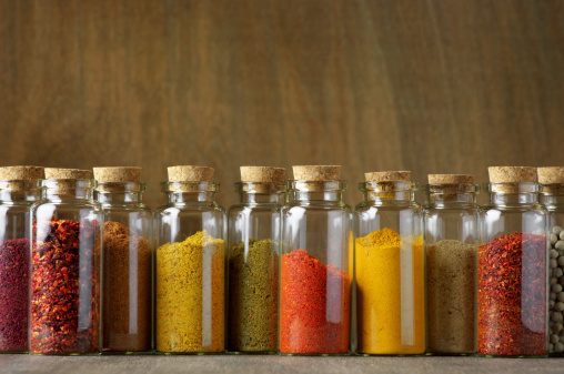 Assorted ground spices in bottles on wooden background.
