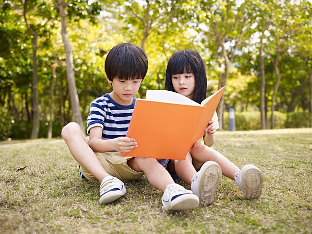 istock asian children reading book outdoors 491376390