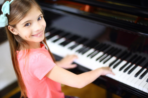 Close up of a little student's hands is playing, learning and practicing the piano. Music abilities for kids. Hobby and activity for the children. Hand of an experienced pianist helping young student.
