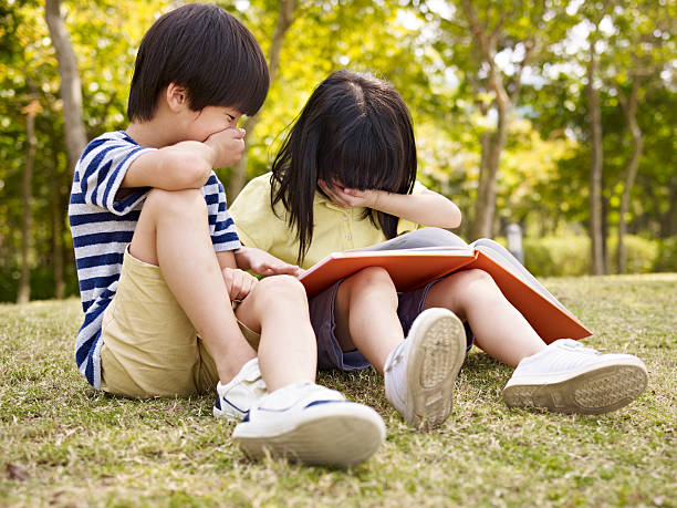 istock asian children reading book outdoors 491378598