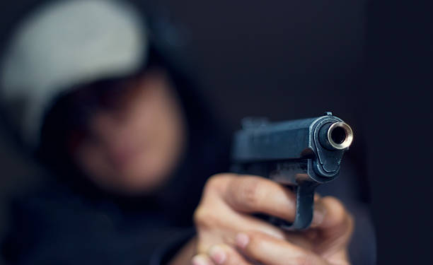 frau zeigt eine waffe im target auf dunklem hintergrund - gun women handgun armed forces stock-fotos und bilder