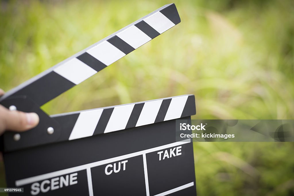 Hand Holding Clapperboard Close-up of hand holding movie clapperboard in nature background. Movie Stock Photo