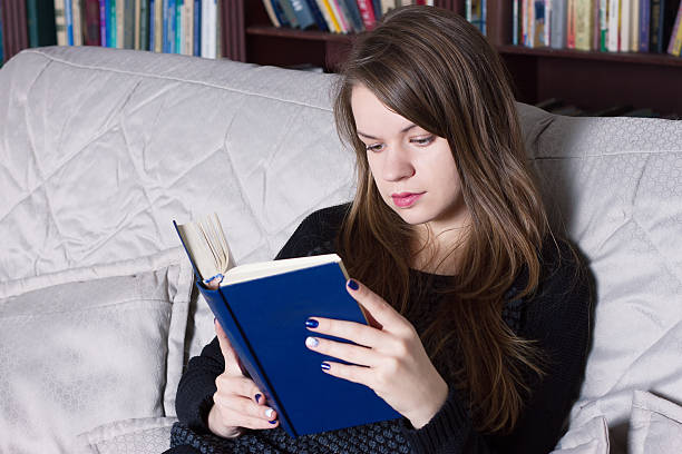 istock Woman at the library reading book 491379674