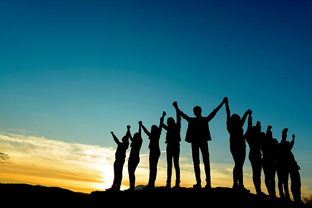 unity people silhouettes at sunset holding arms raised. unity silhouette people holding hands stock pictures, royalty-free photos & images