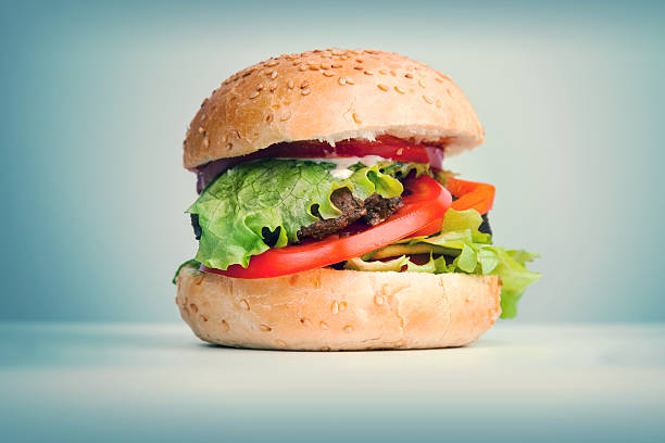 istock Big hamburger lays on the table above blue background 491381583