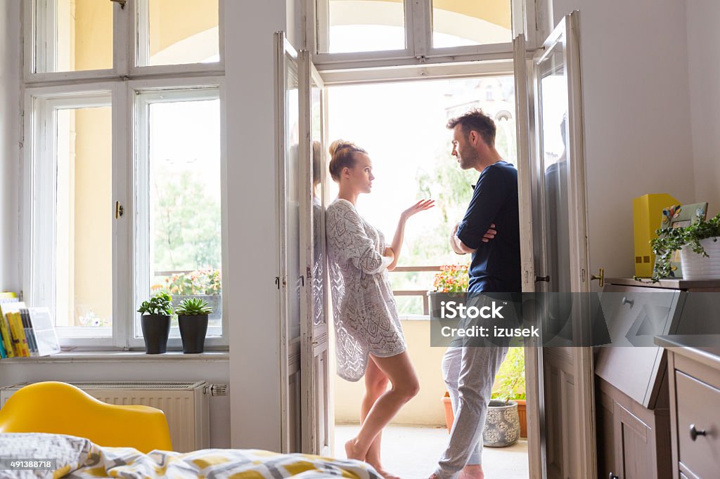 Couple arguing in the morning at home Couple agruingm stadning in the open window at home in the morning. Couple - Relationship Stock Photo
