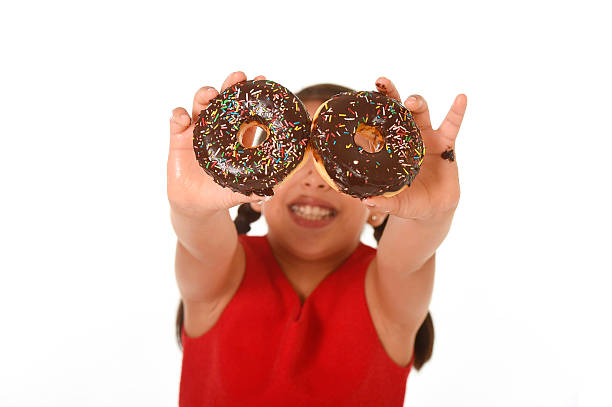istock happy child in red dress playing with chocolate donuts 491389196