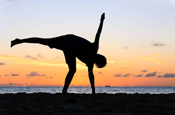 istock Silhouette of young man doing yoga at sunset 491393552