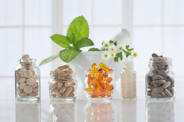 medicina herbaria pastillas y mortero durante un fondo brillante - complemento vitamínico fotografías e imágenes de stock
