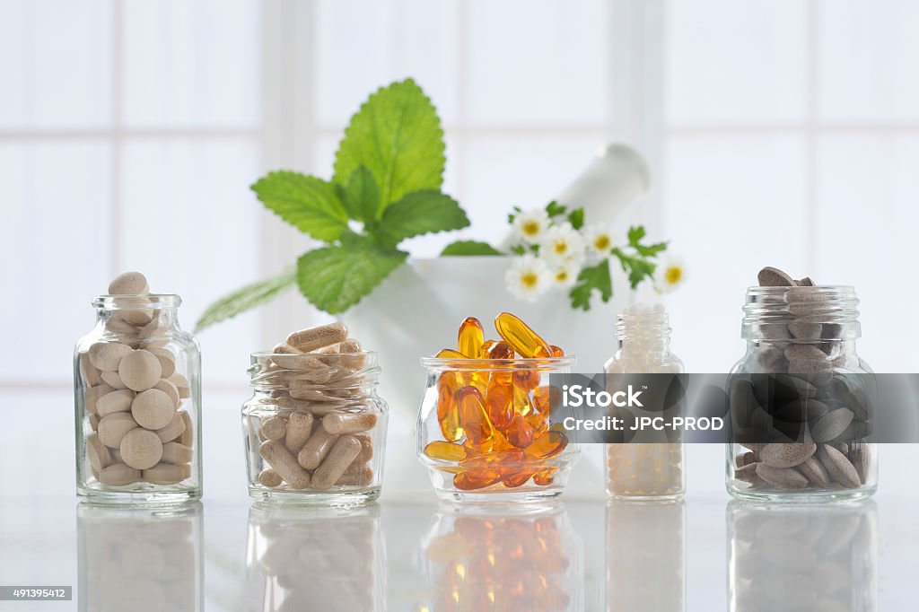 Herbal medicine pills and mortar over bright  background Alternative health care fresh herbal ,dry and herbal capsule with mortar Nutritional Supplement Stock Photo