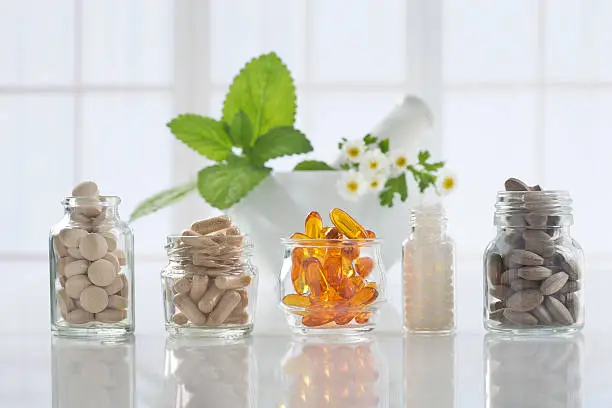 Photo of Herbal medicine pills and mortar over bright  background