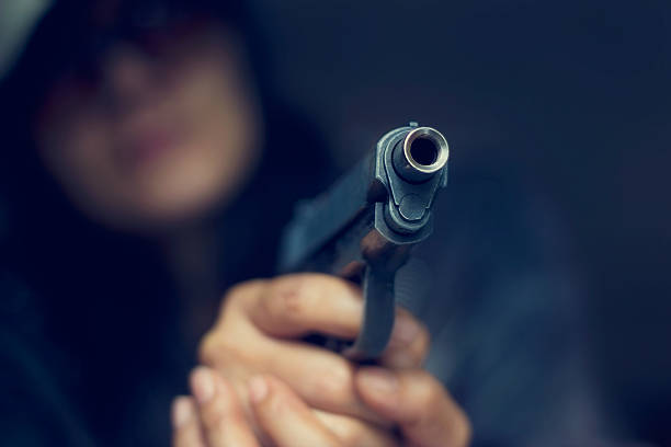mulher apontando uma arma no alvo em fundo escuro - gun women handgun armed forces - fotografias e filmes do acervo