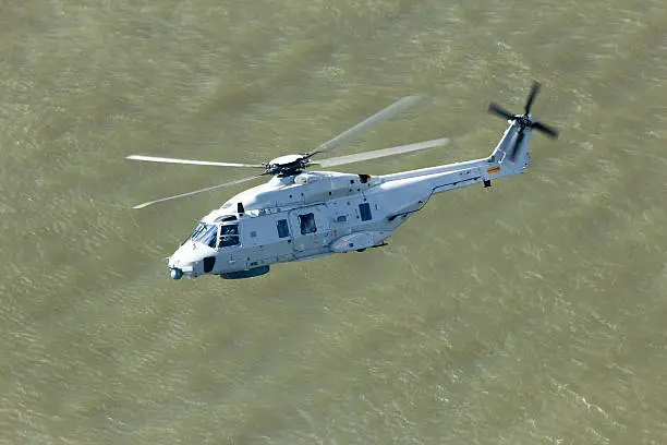 Navy helicopter flying over water.