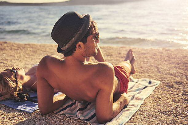 Soaking up some sun Shot of a man relaxing on the beach next to his girlfriendhttp://195.154.178.81/DATA/i_collage/pu/shoots/805670.jpg sunbathing stock pictures, royalty-free photos & images